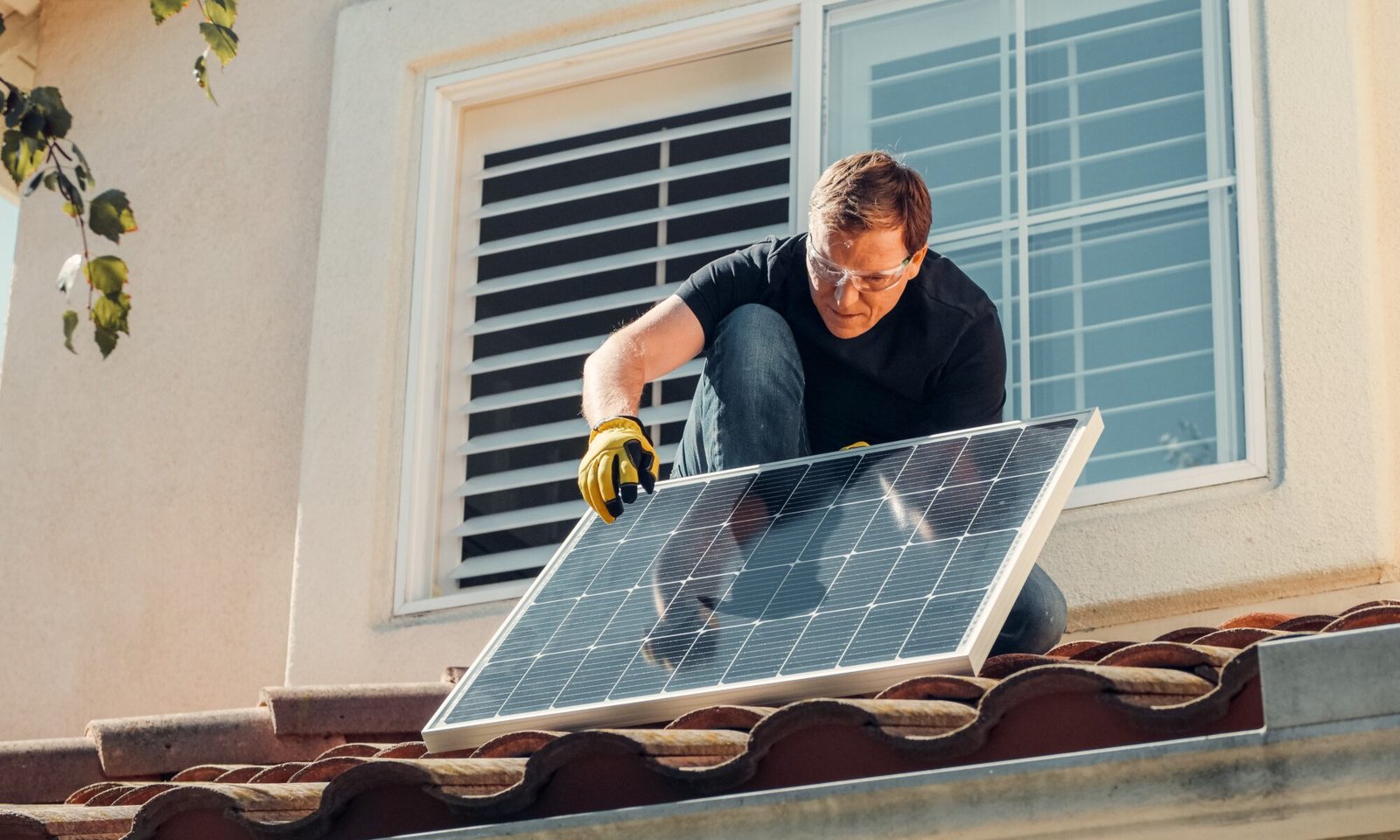 instalador subindo no telhado com placa solar para usufruir das vantagens da energia solar